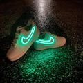 Customized Air Force 1 Sneakers with Neon Lights glowing in vibrant green on a dark reflective surface.